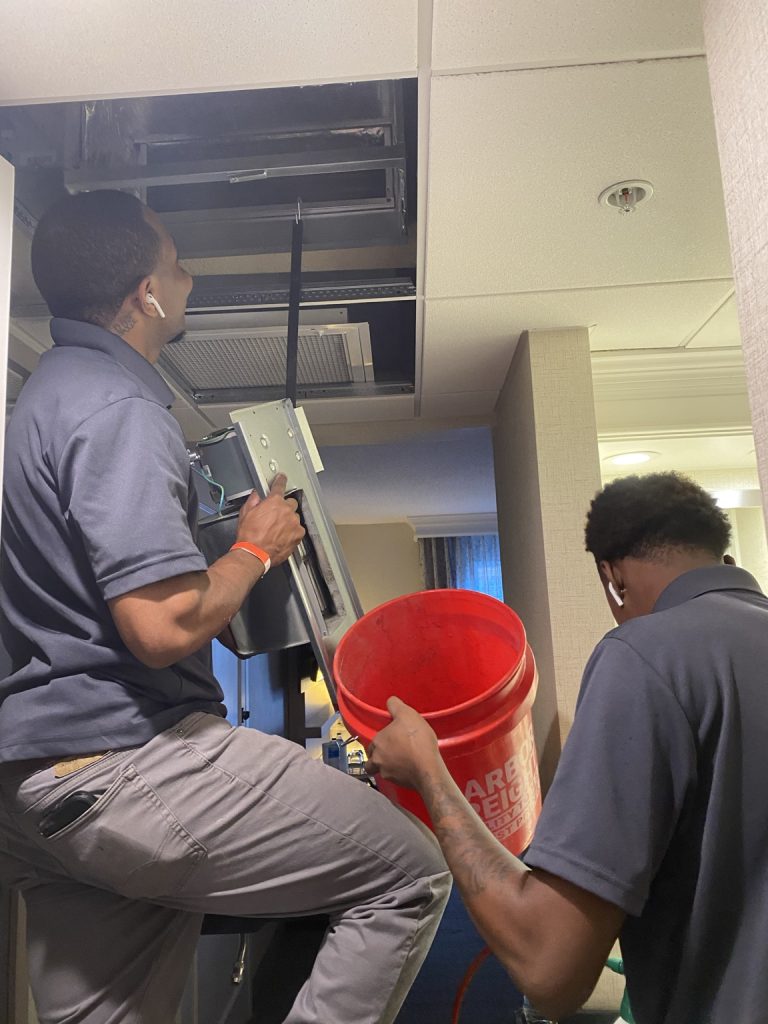 Hotel HVAC cleaning and restoration technicians servicing guestroom HVAC equipment